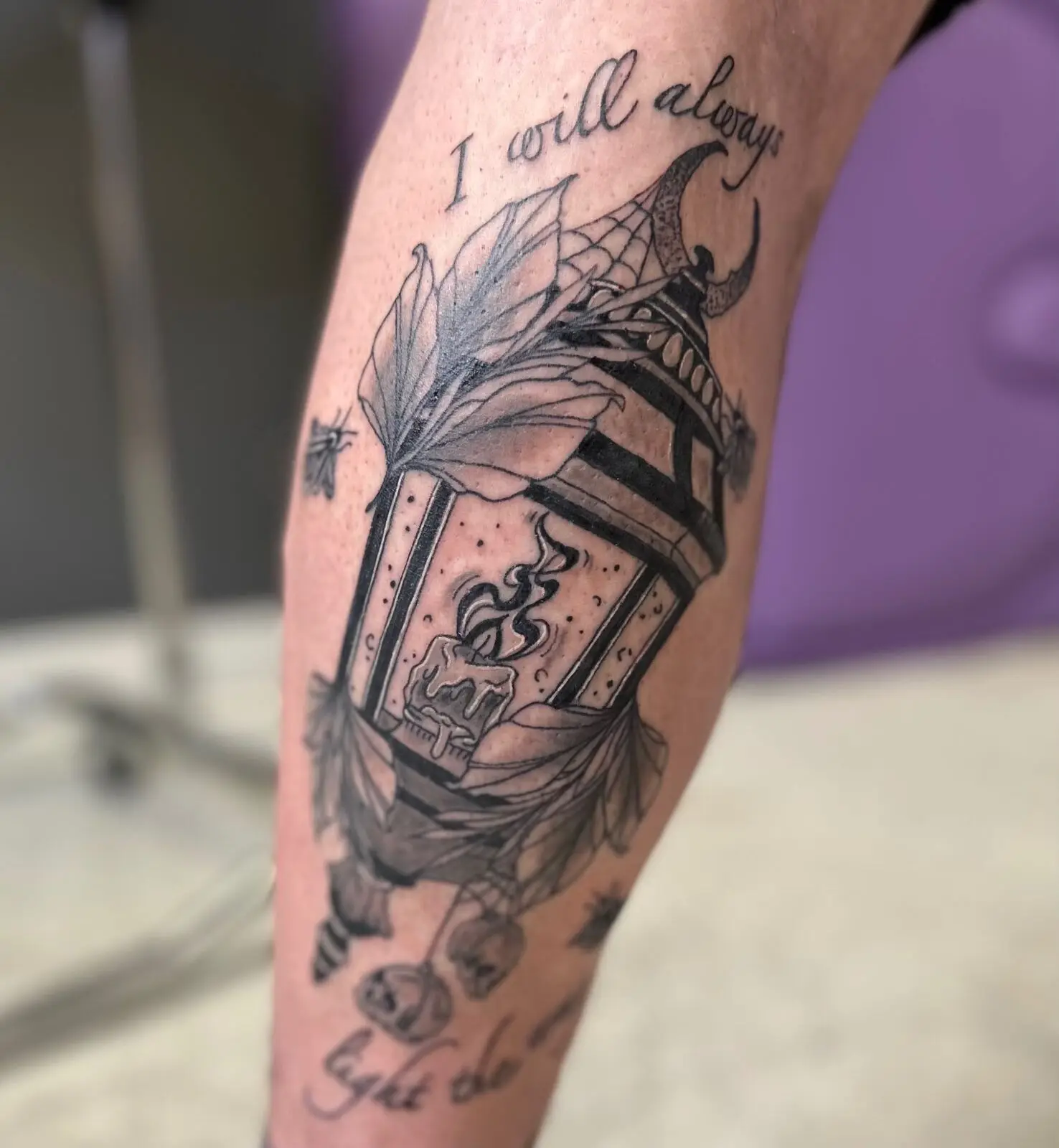 Black and grey ornate lantern with lily, candle and crescent moon calf tattoo with 'I will always' script